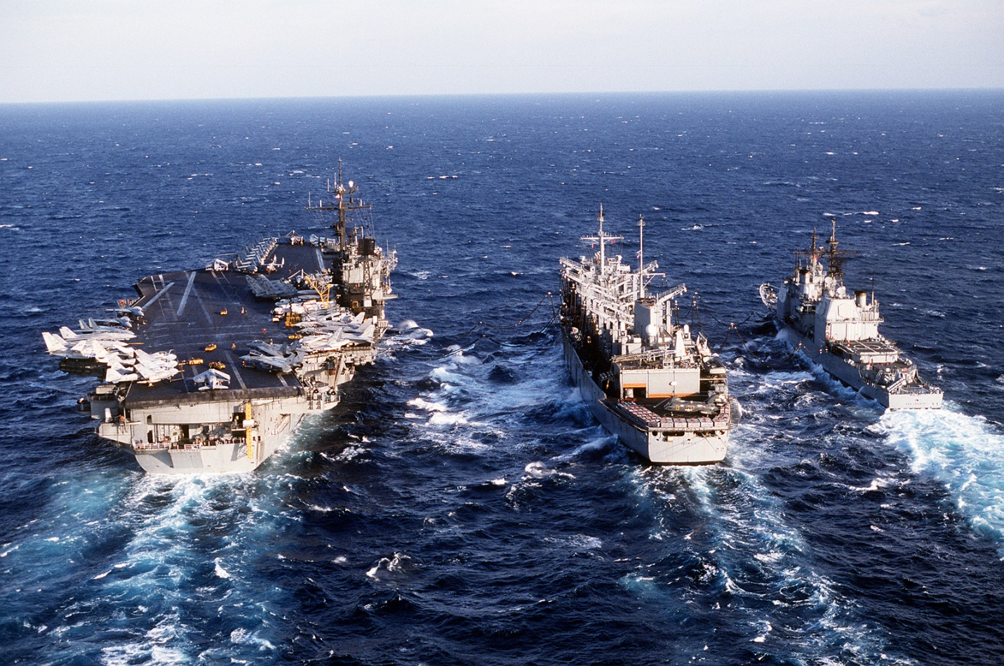 The fast combat support ship USS DETROIT (AOE-4) is flanked by the aircraft carrier USS